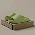 Pair of green thick-soled cloud slides on a display box