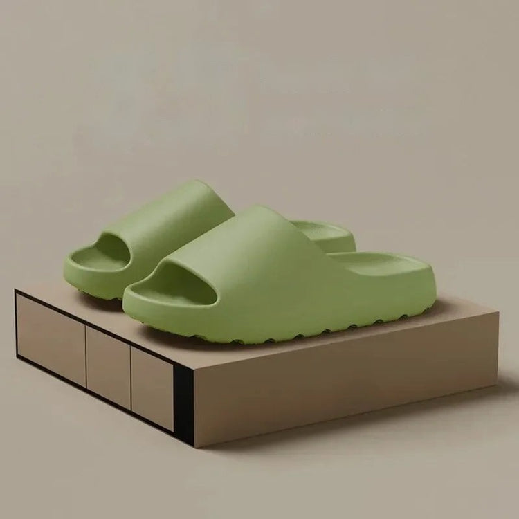 Pair of green thick-soled cloud slides on a display box